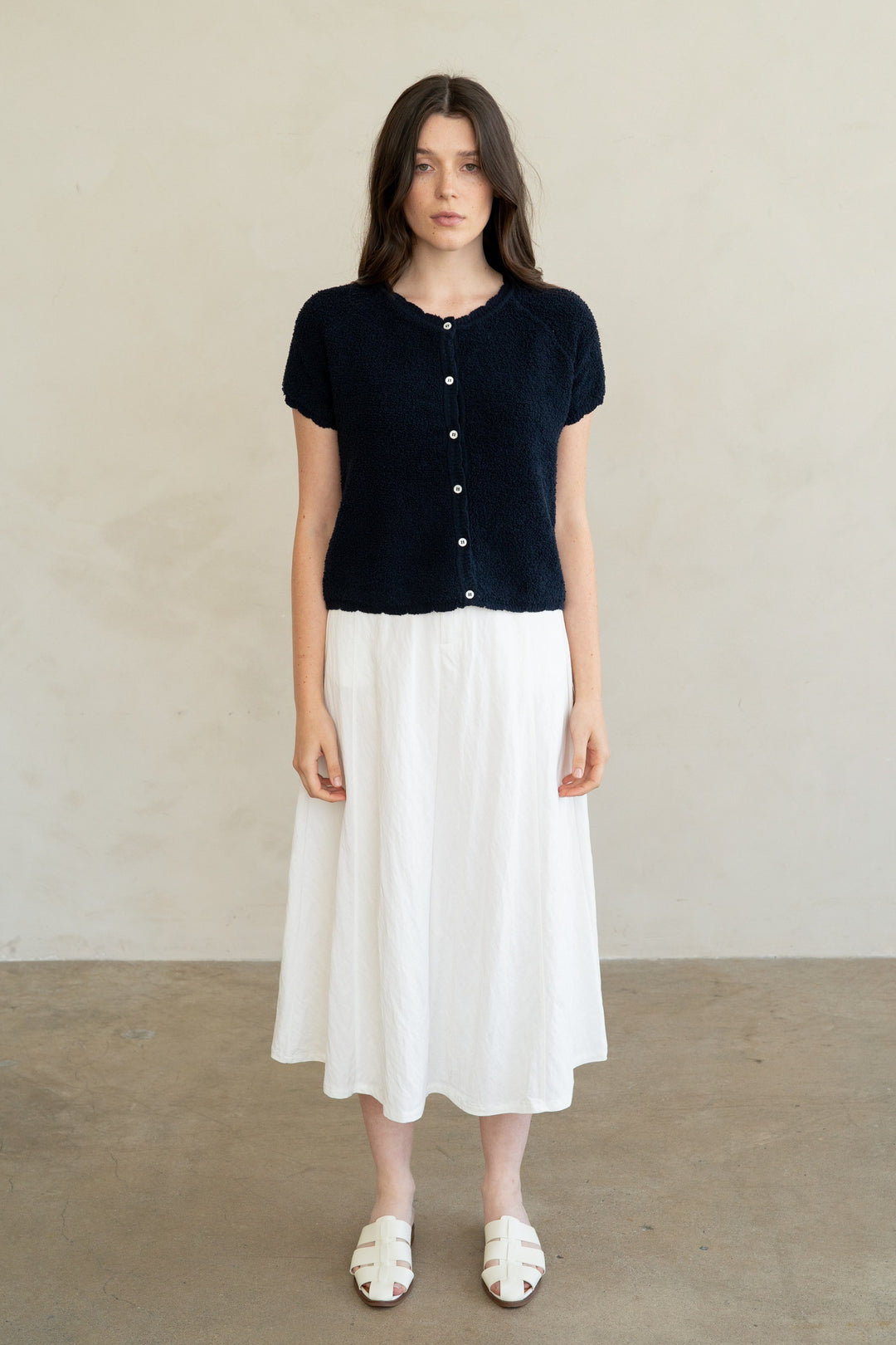 Woman wearing a navy blue Amelia Soft Form Textured Knit Cardigan with a white midi skirt.