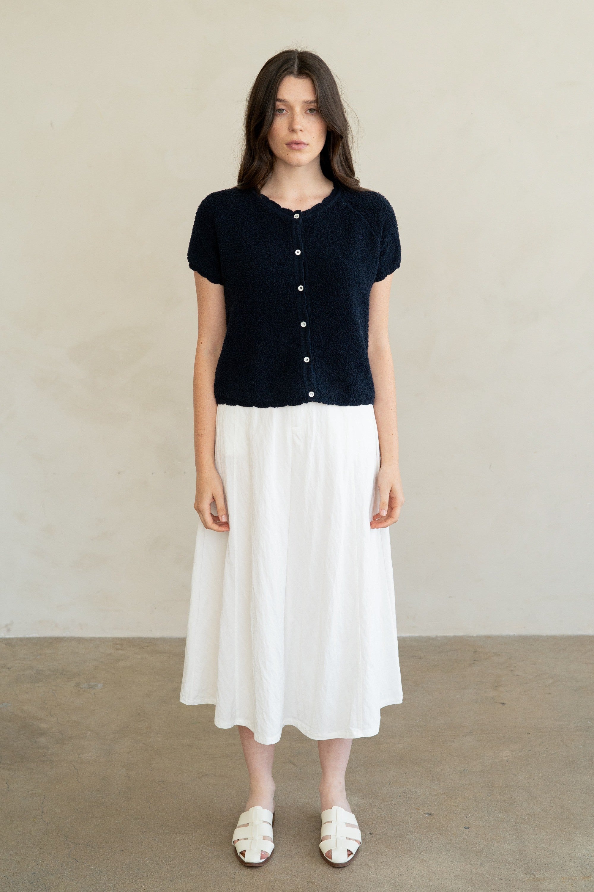 Woman wearing a navy blue Amelia Soft Form Textured Knit Cardigan with a white midi skirt.