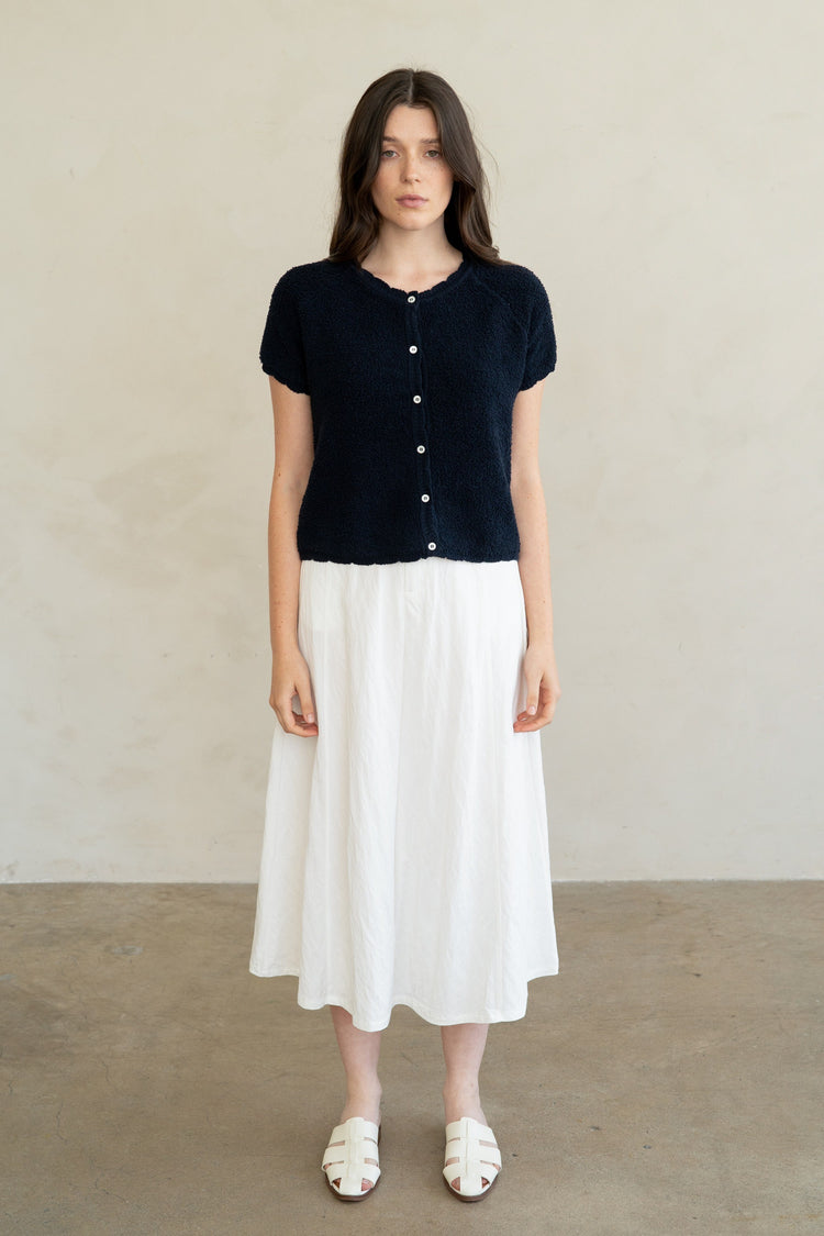 Woman wearing a navy blue Amelia Soft Form Textured Knit Cardigan with a white midi skirt.