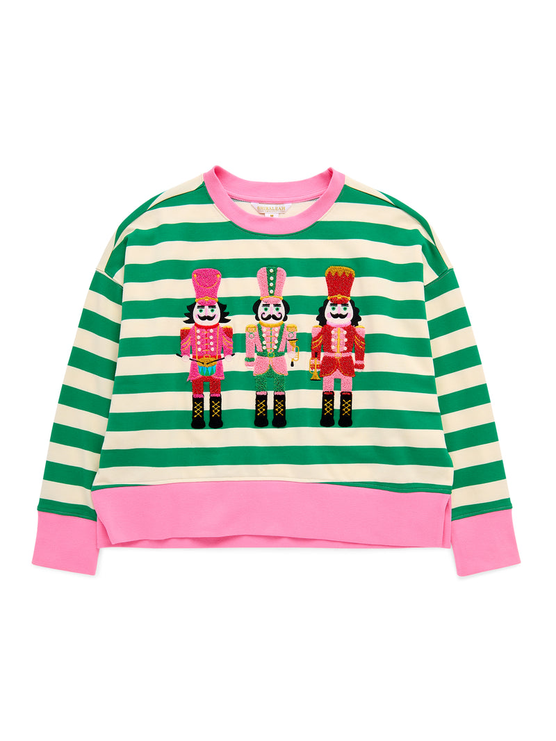 Green and white striped sweatshirt with three embroidered nutcrackers and pink trim.