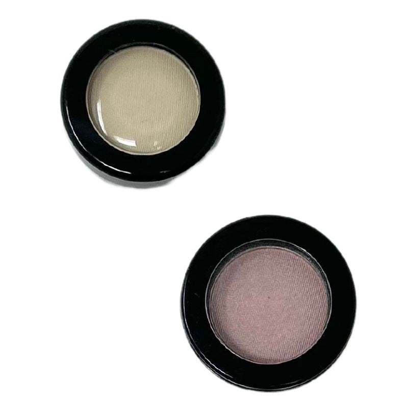 Two round black compacts containing light beige and dusty mauve matte eye shadows.