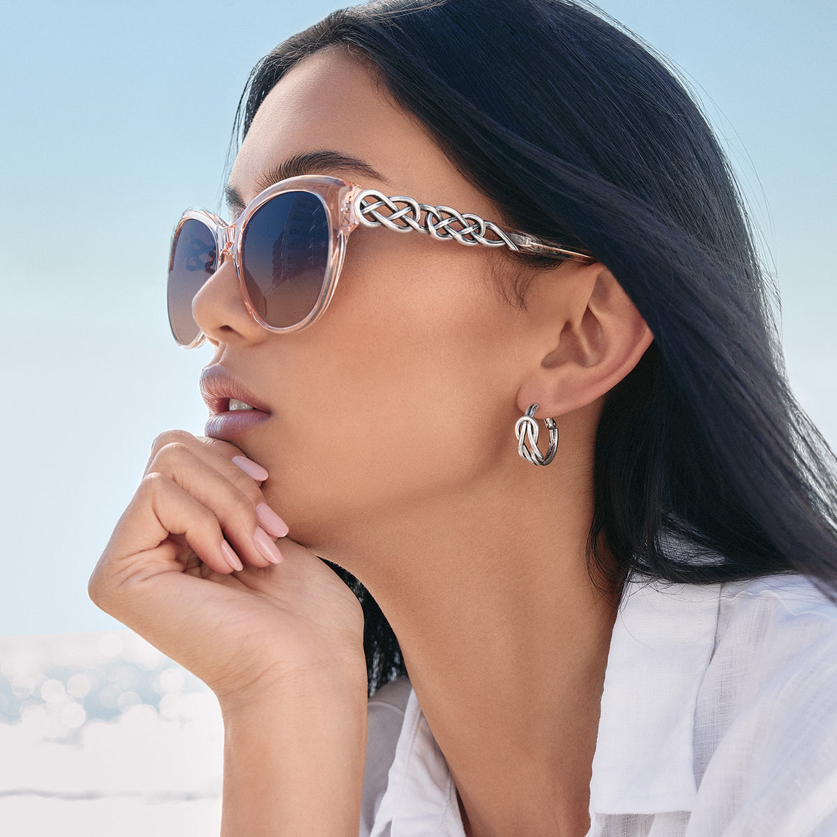 Woman wearing Interlok Braid cat eye sunglasses in Rosewater with silver plated braid temples.