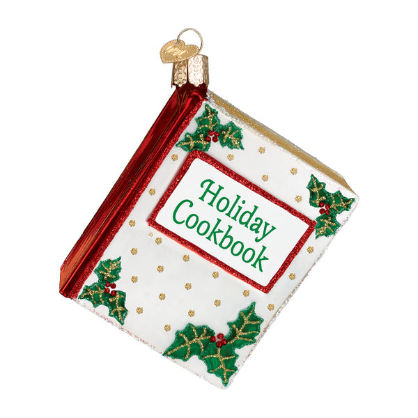 Glass Christmas Cookbook ornament with red spine, holly accents, and gold glitter details.