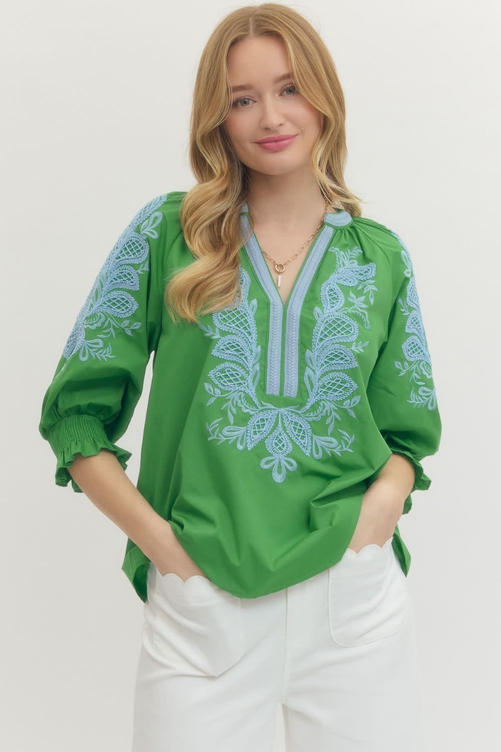Woman wearing a green Madelyn top with light blue embroidery, split V-neck, and 3/4 elastic sleeves.
