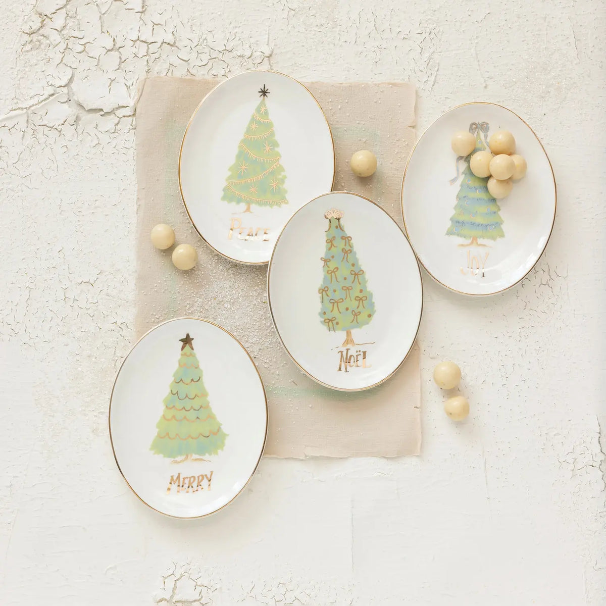 Oval stoneware dish with festive holiday word text in white on a neutral background.