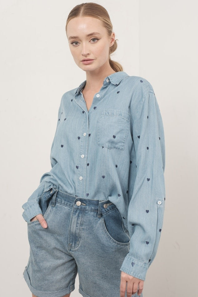 Front view of Naomi oversized chambray shirt in denim blue with heart embroidery detail and adjustable sleeves.