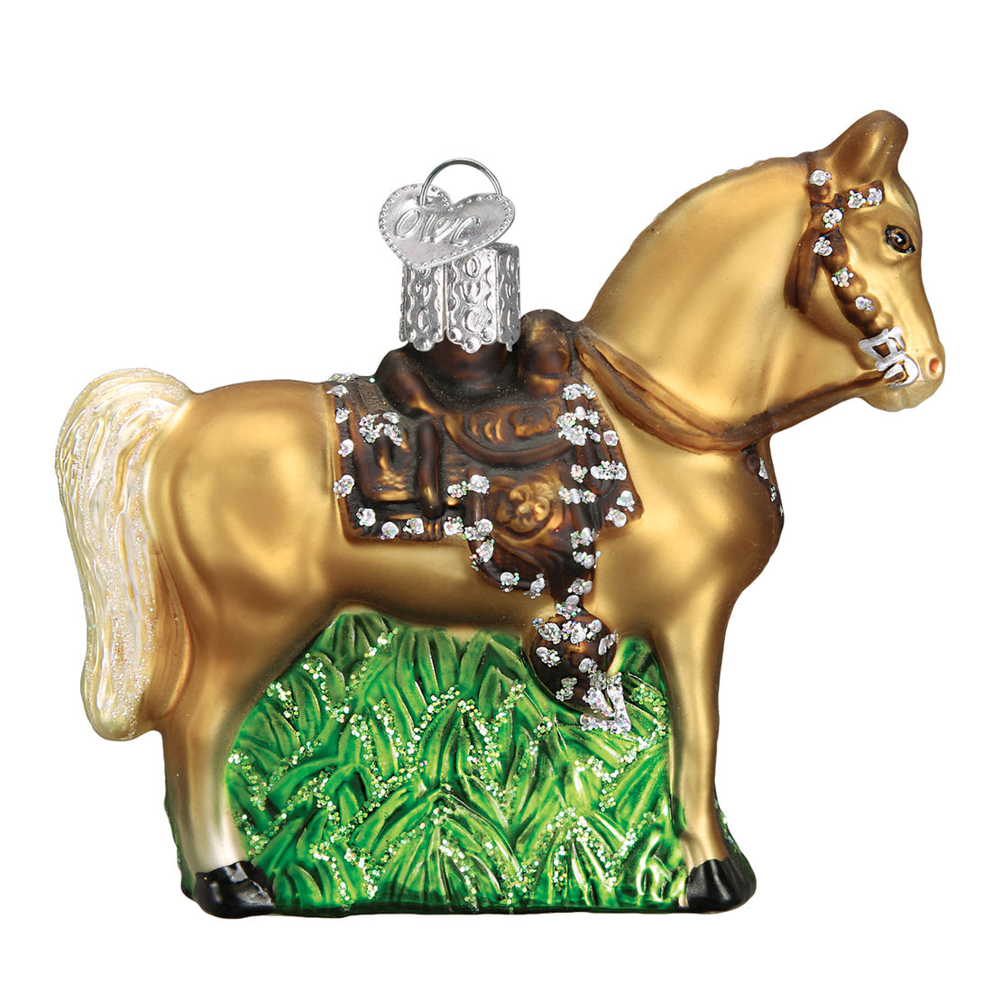Glass western horse ornament with a gold body, brown saddle, and glitter accents on green grass.