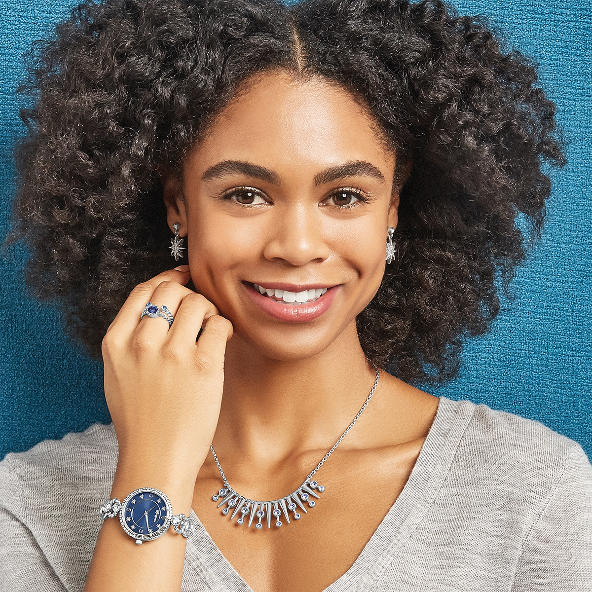 Woman wearing Radiant Star silver post earrings with crystal accents and matching jewelry.