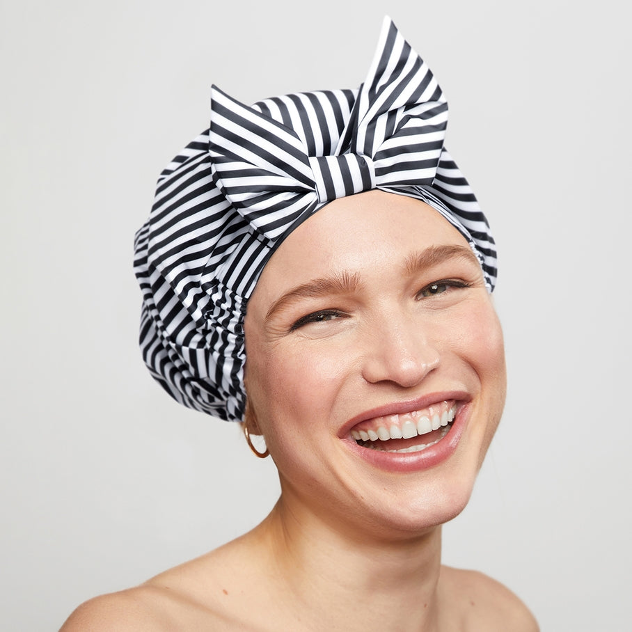 Black shower cap with white stripes featuring a non-slip silicone grip edge.