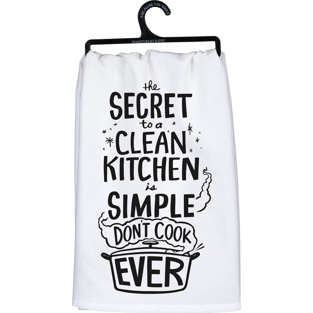 White cotton kitchen towel with black text reading 'the secret to a clean kitchen is simple: don't cook EVER' and a pot illustration.