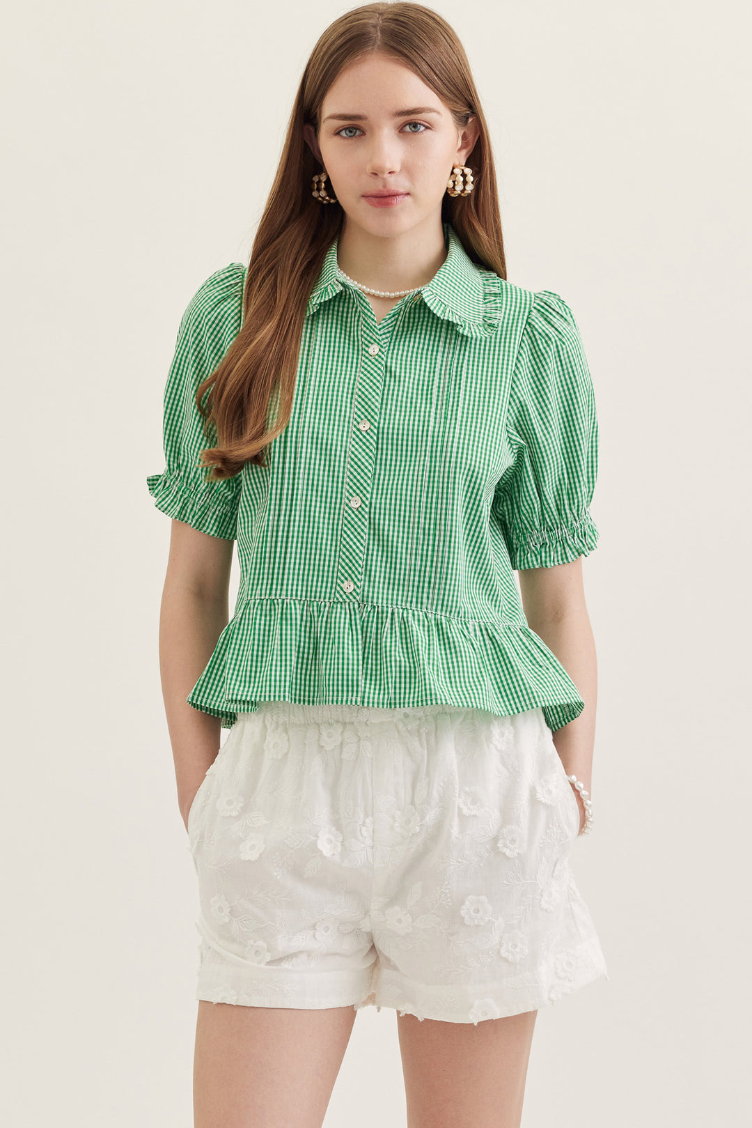 Woman wearing the green and white gingham Katie Collared Blouse with short puff sleeves.