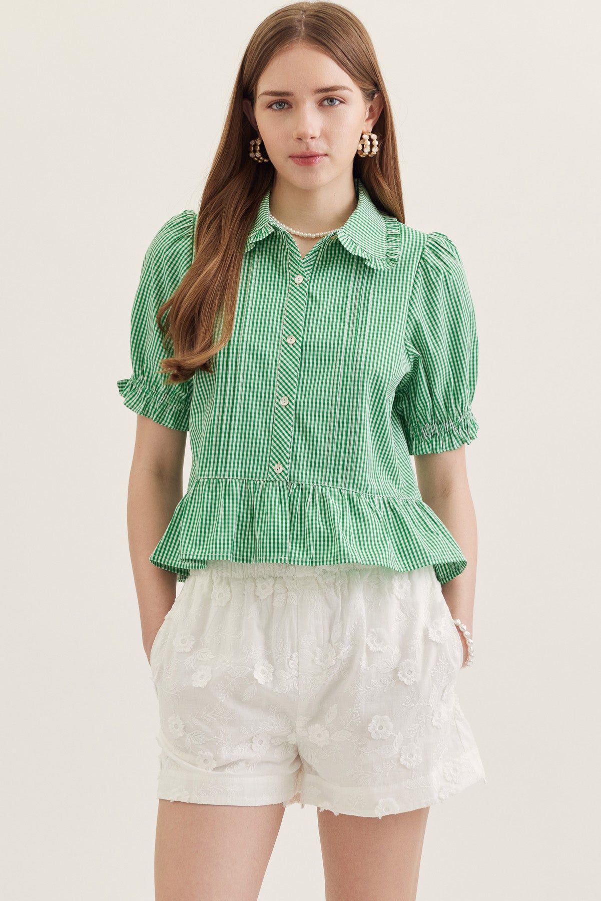 Woman wearing the green and white gingham Katie Collared Blouse with short puff sleeves.
