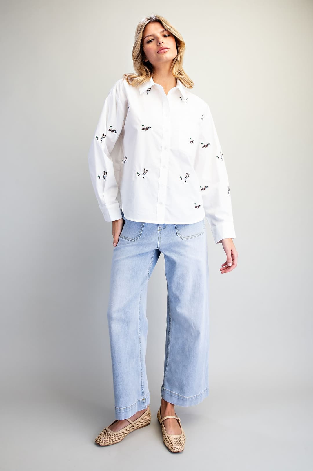 Woman wearing a white Lainey button down shirt with embroidered mallard ducks and light wash jeans.