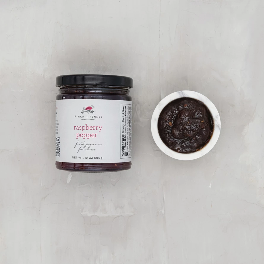 Jar of raspberry pepper fruit preserves with visible red berries.