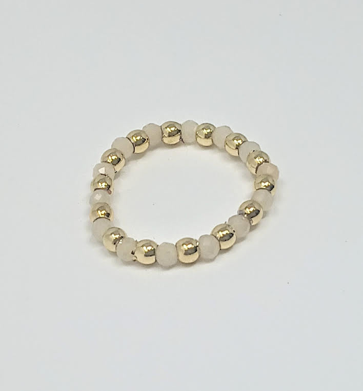 A ring made of alternating 3mm gold-toned metal beads and small, pale semi-precious stone beads.