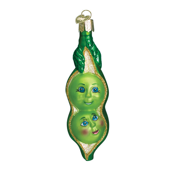 Two Peas In A Pod glass Christmas ornament with hand-painted faces and gold glitter accents.