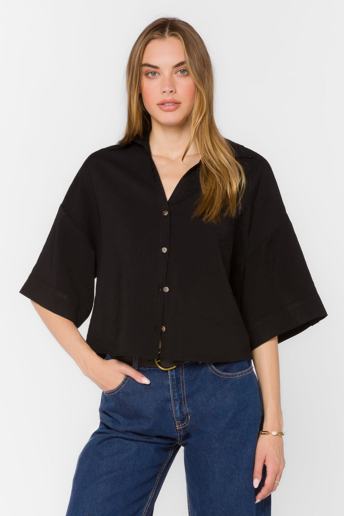 Woman wearing a black Minx Shirt with elbow-length sleeves and a button-front closure.