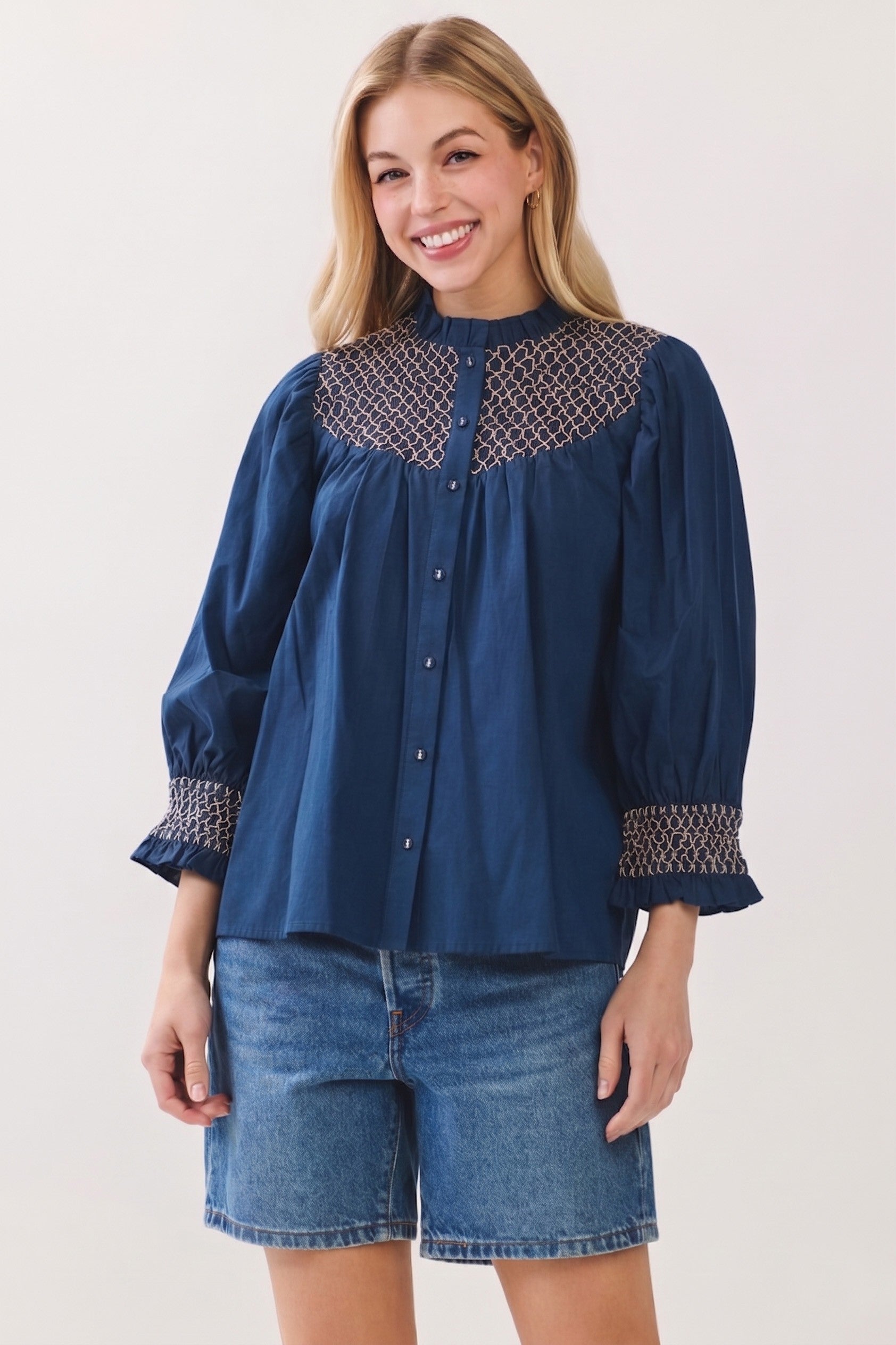 Woman wearing a navy blue Jenny Embroidered Button Down Blouse Top with denim shorts.