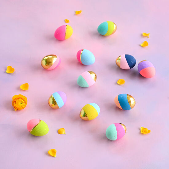 Small papermache eggs decorated with gold accents and pastel color blocks.