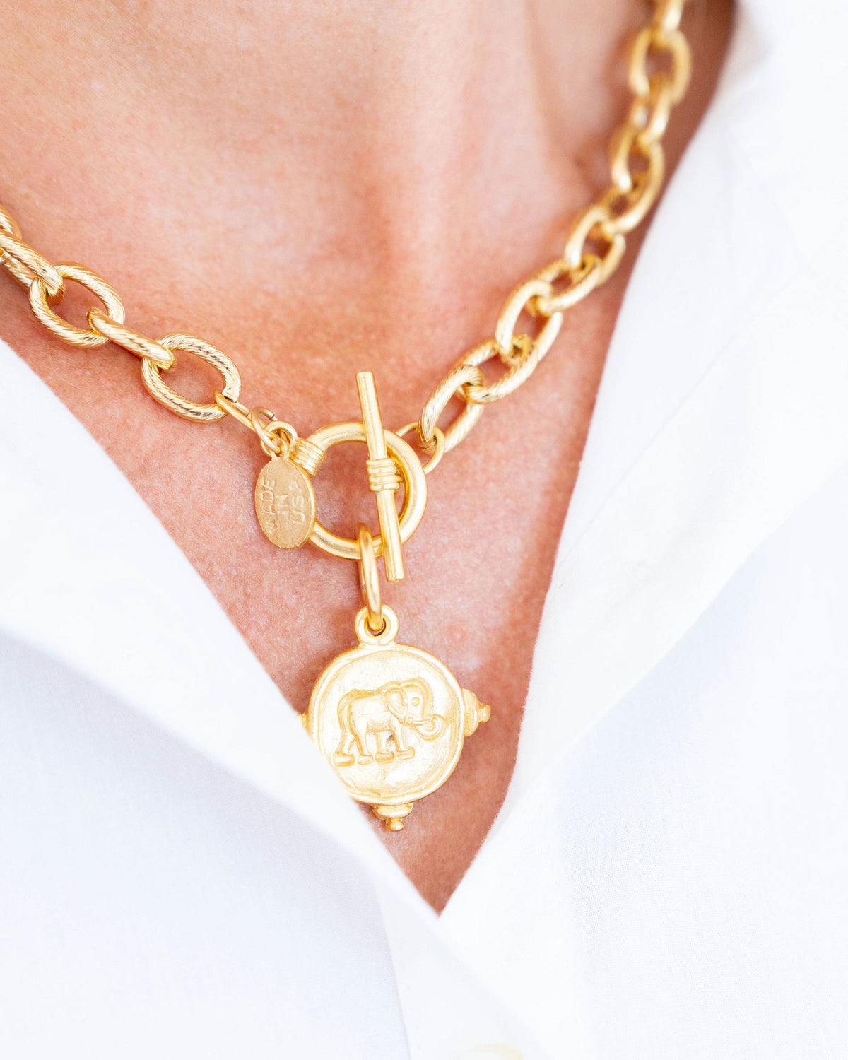 Gold elephant toggle necklace with a 24k gold-plated chain and coin pendant on a person.
