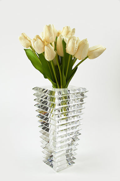 Small crystal inverted pyramid cut vase with white tulips on a white background.