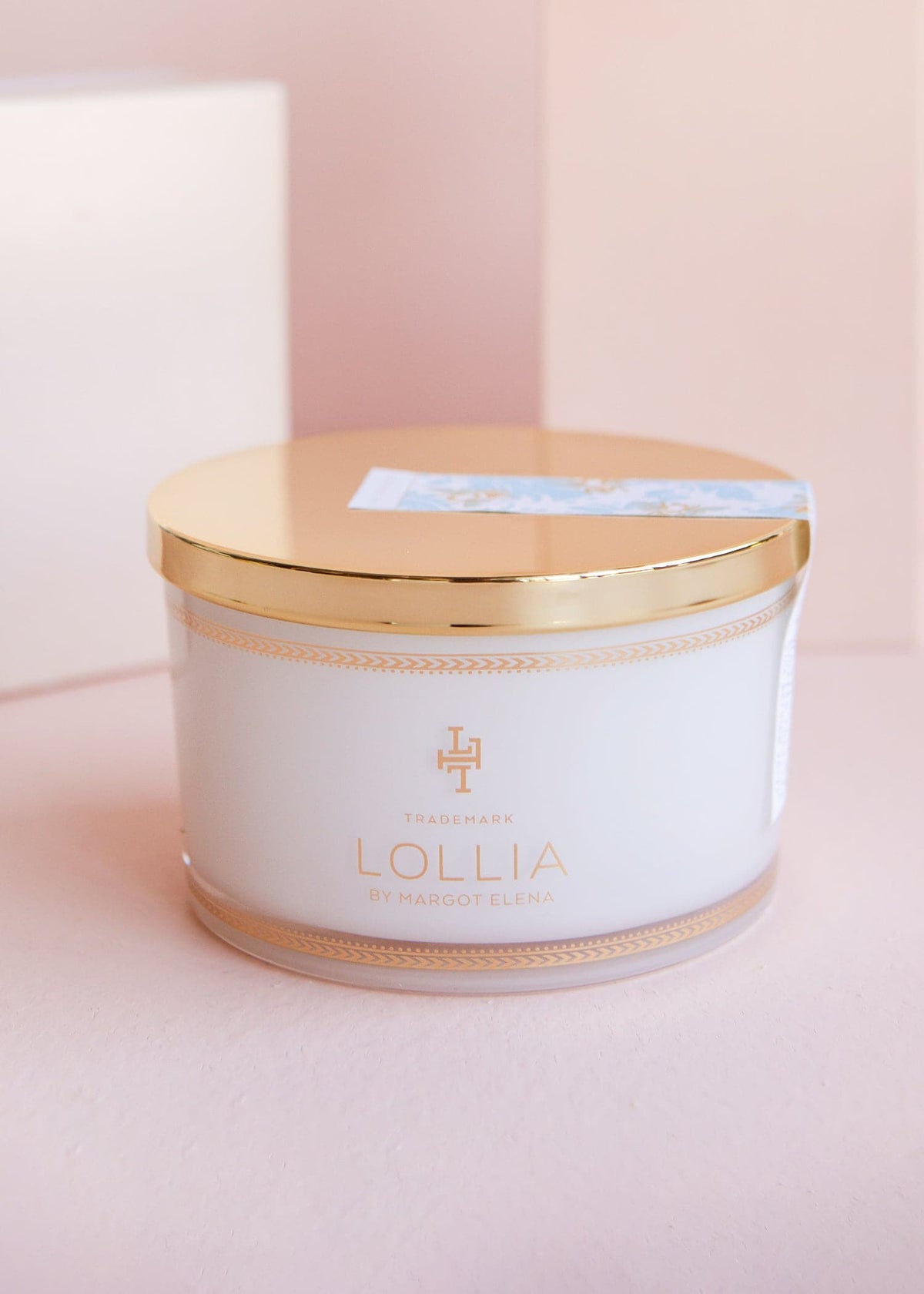 White glass jar with gold accents holding sea salt in a linen bag