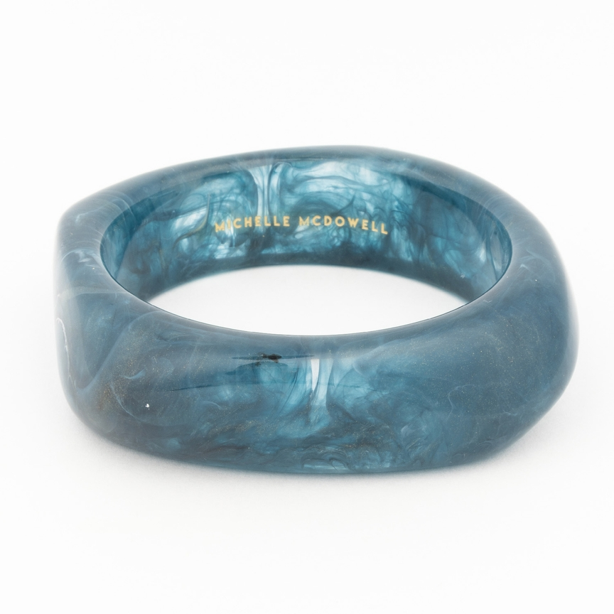 Tillie Bangle in marbled teal resin with gold Michelle McDowell branding on the interior.