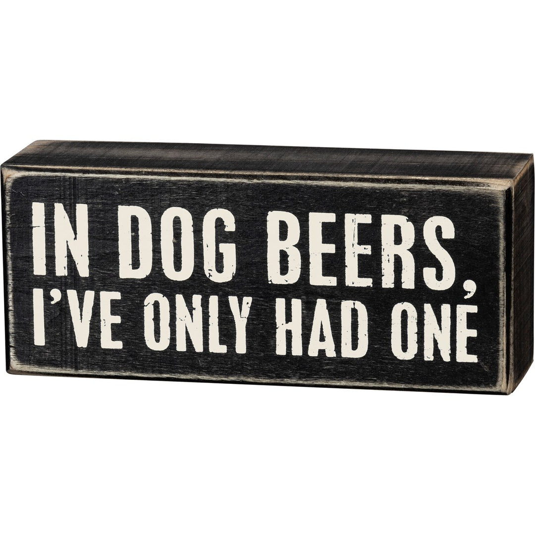 Black wooden box sign with white text reading 'IN DOG BEERS, I'VE ONLY HAD ONE'.