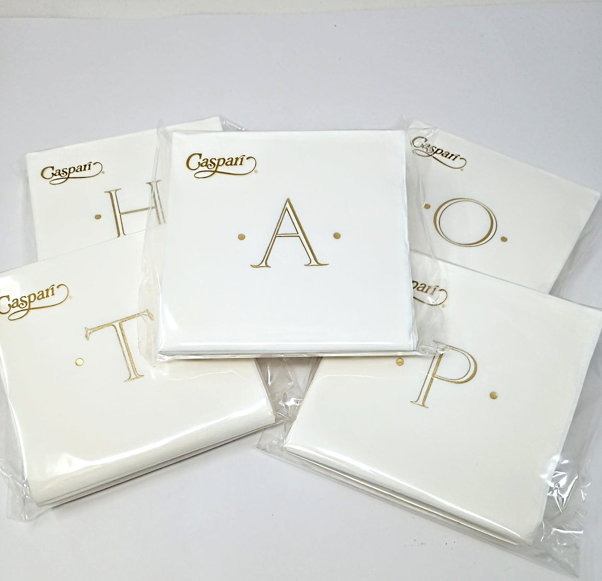 White paper cocktail napkin with an initial letter monogram printed in a subtle tone.
