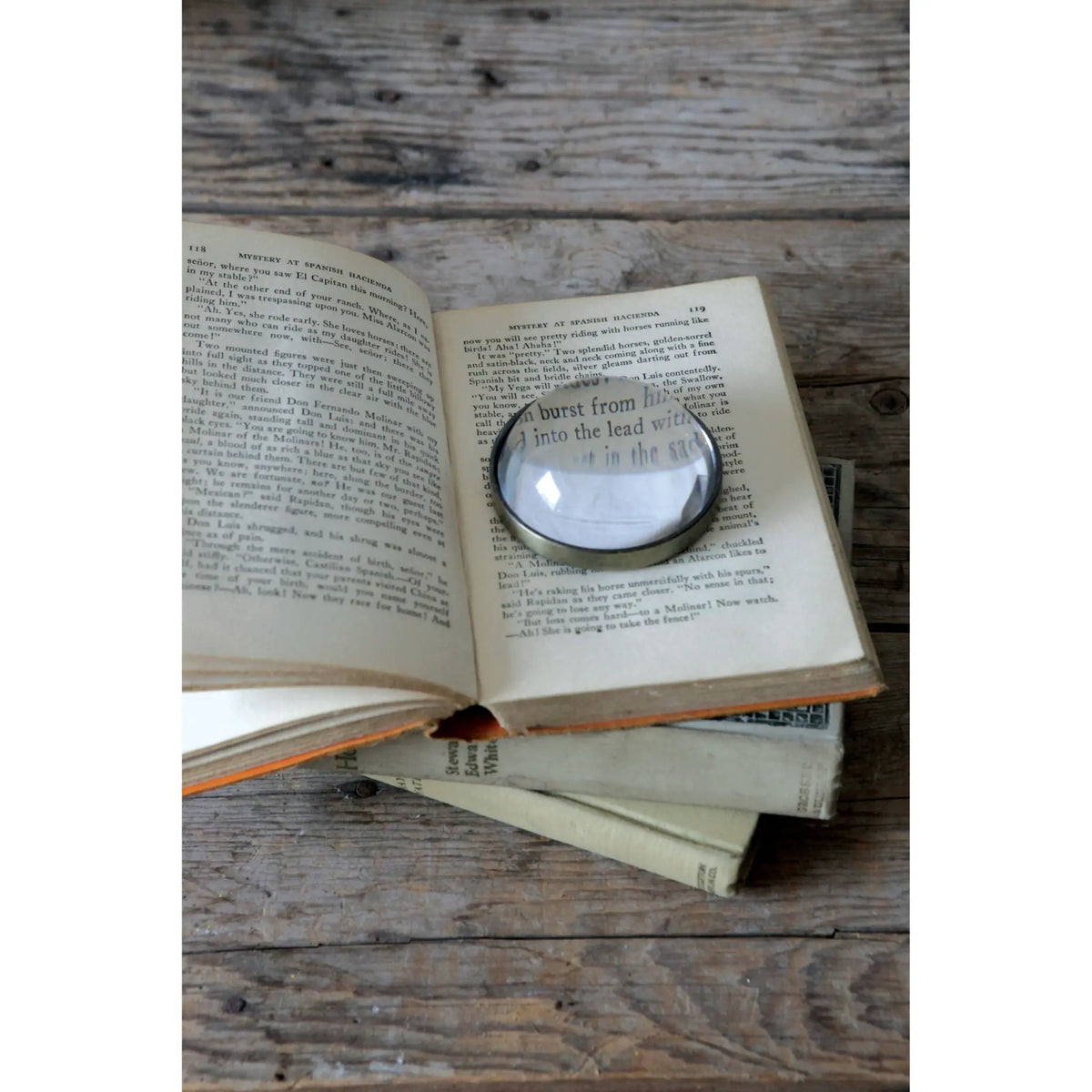 Glass magnifying glass paperweight with wooden base in clear finish.
