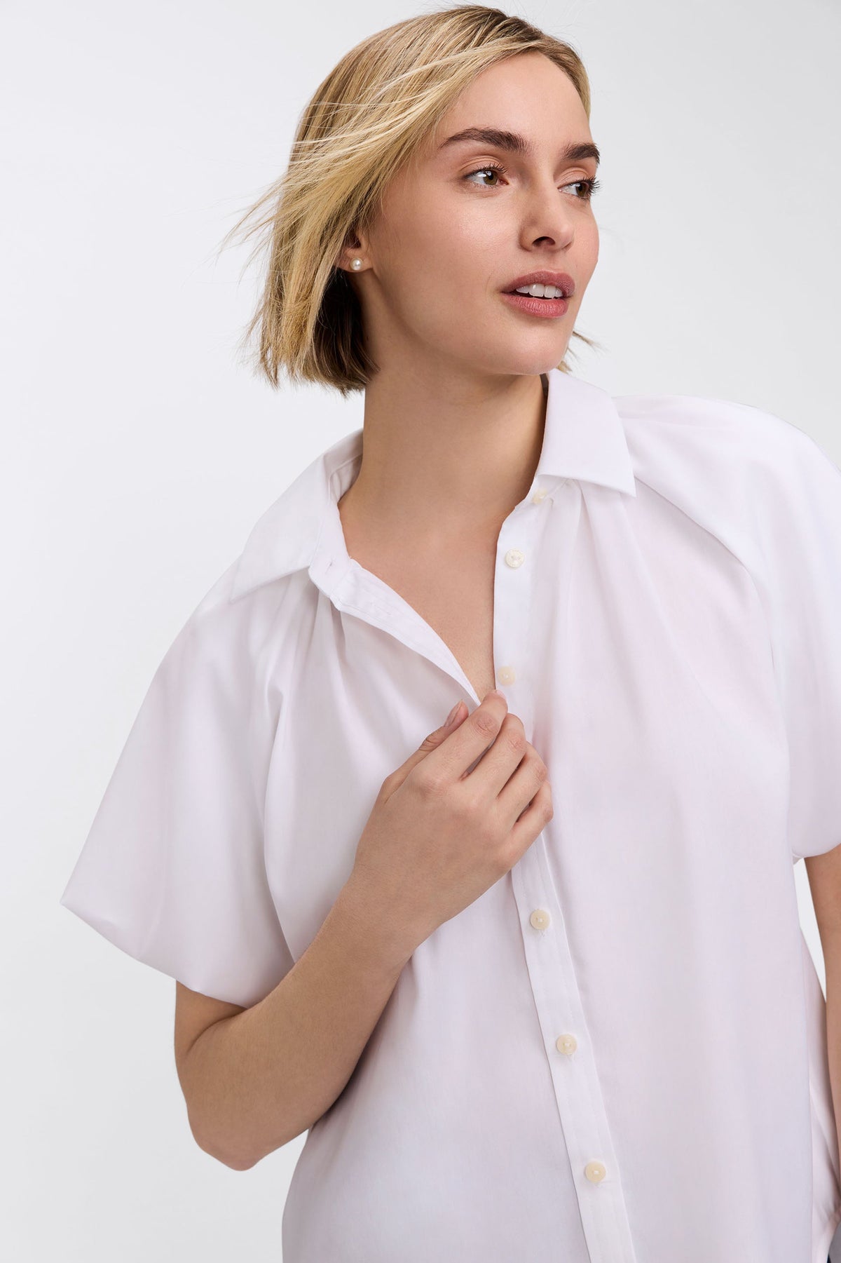 Woman wearing a white Paula Solid Puff Sleeve Shirt with a point collar and button-front placket.