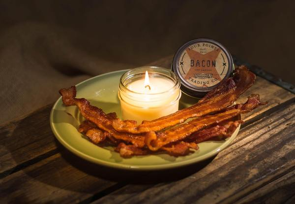 Bacon soy candle in a clear glass jar with an off-white braided wick and visible wax.