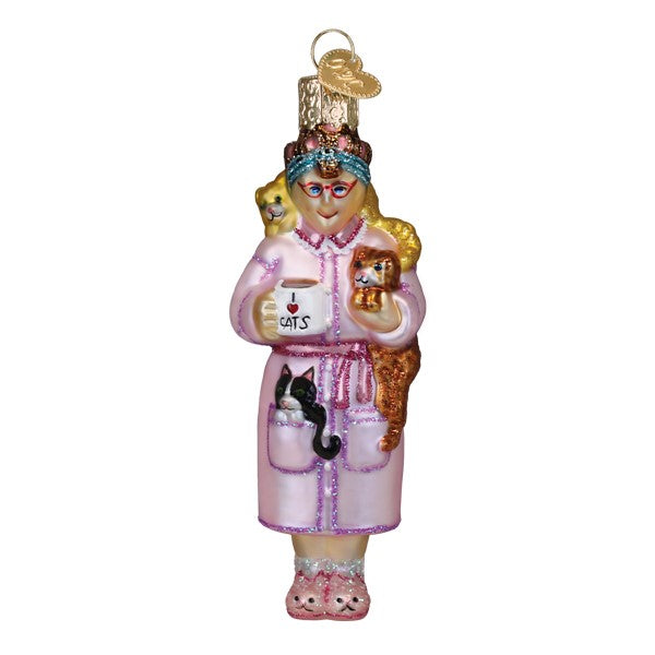 Glass Christmas ornament of a woman in a pink robe holding a mug and surrounded by several cats.