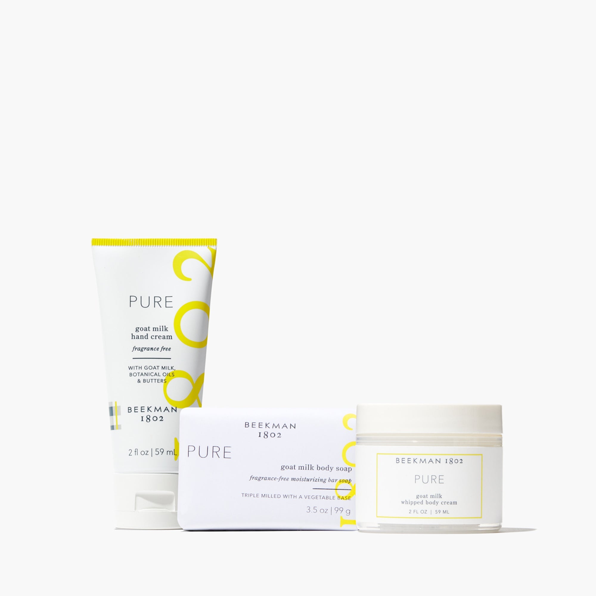 Three travel-sized Pure goat milk body care items: soap, whipped cream, and hand cream in white packaging.