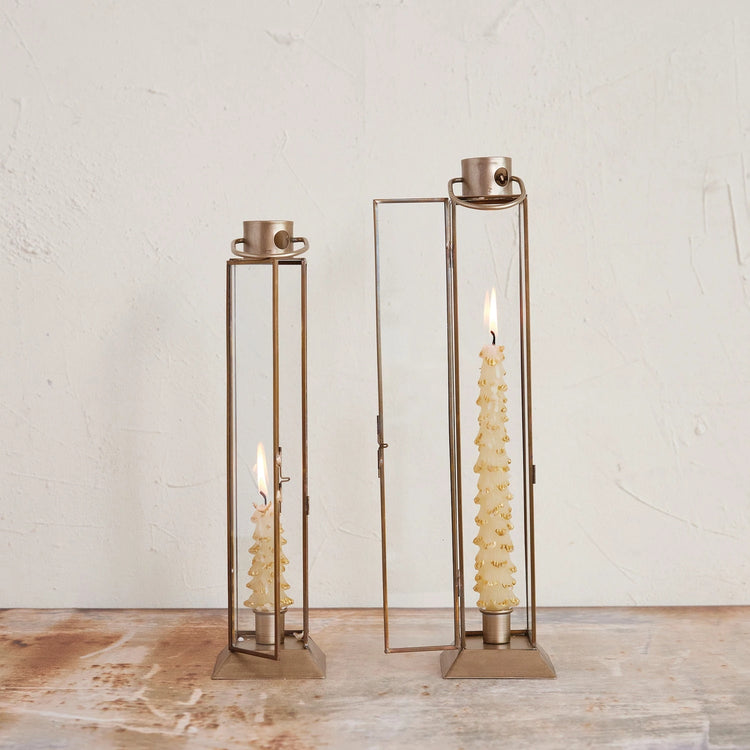 Two gold finish metal and glass lantern taper holders with lit tree-shaped candles.