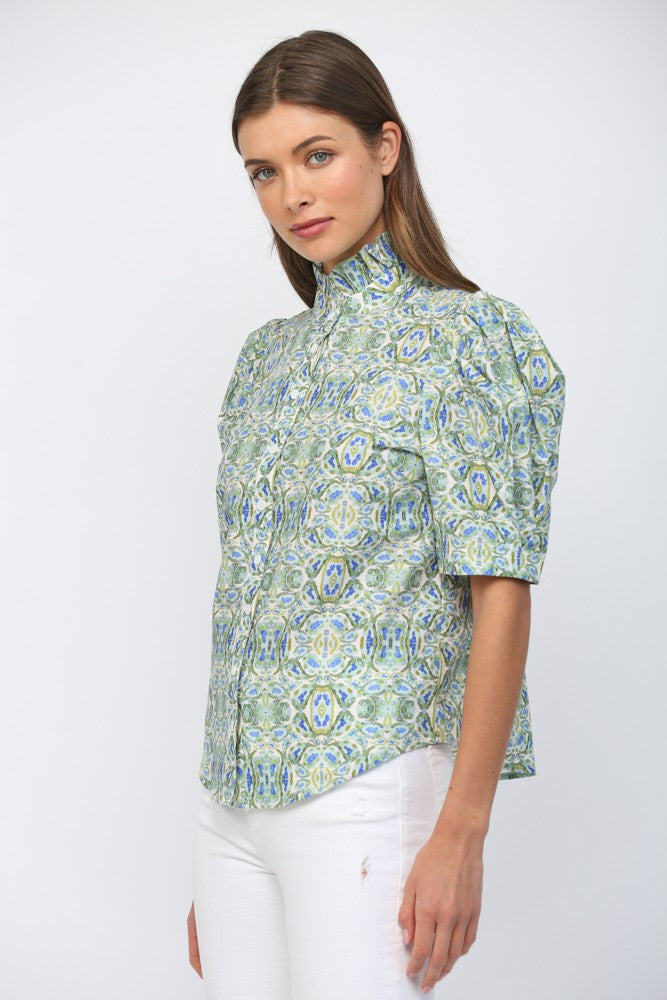 Woman wearing Eliana puff short sleeve ruffle neck button down top in a green and blue pattern.
