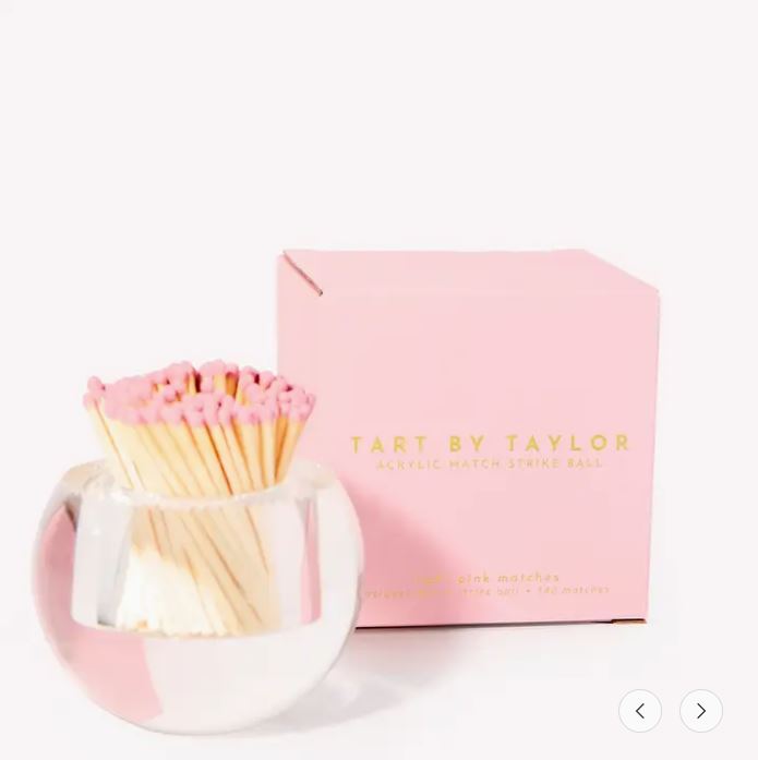 Round acrylic match strike ball with pink-tipped matches next to its pink branded box.