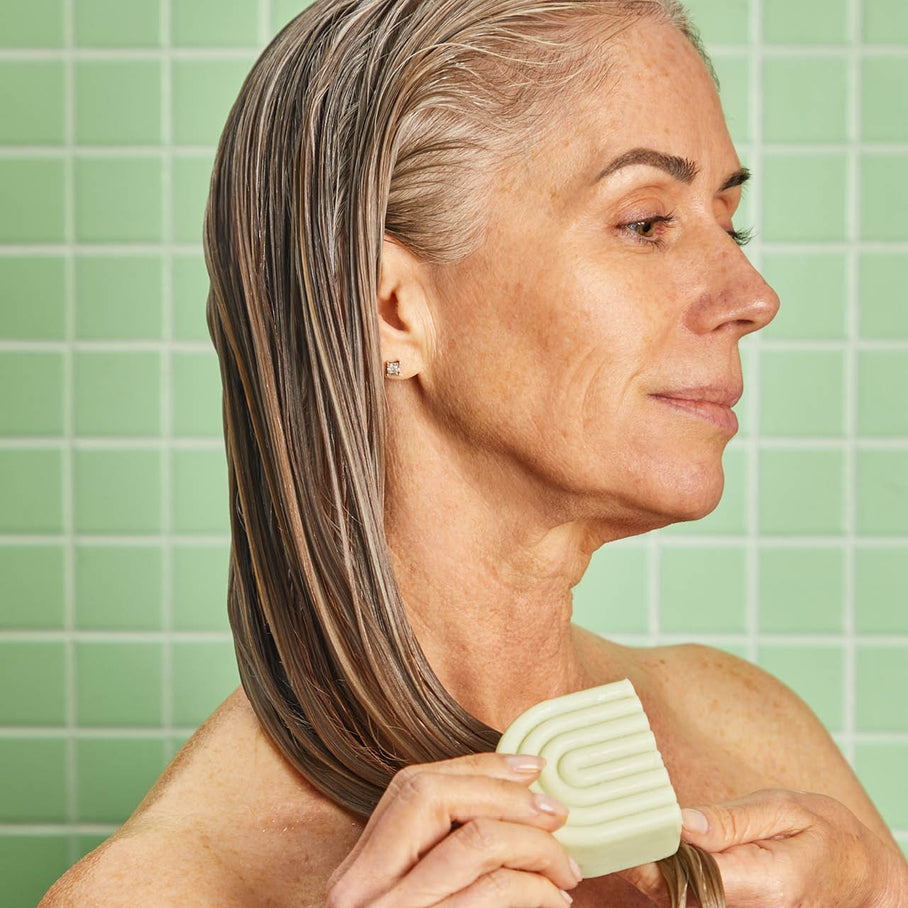 Solid conditioner bar in a clear container with tea tree and mint ingredients.