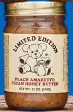 Jar of peach-colored amaretto pecan honey butter with a white lid.