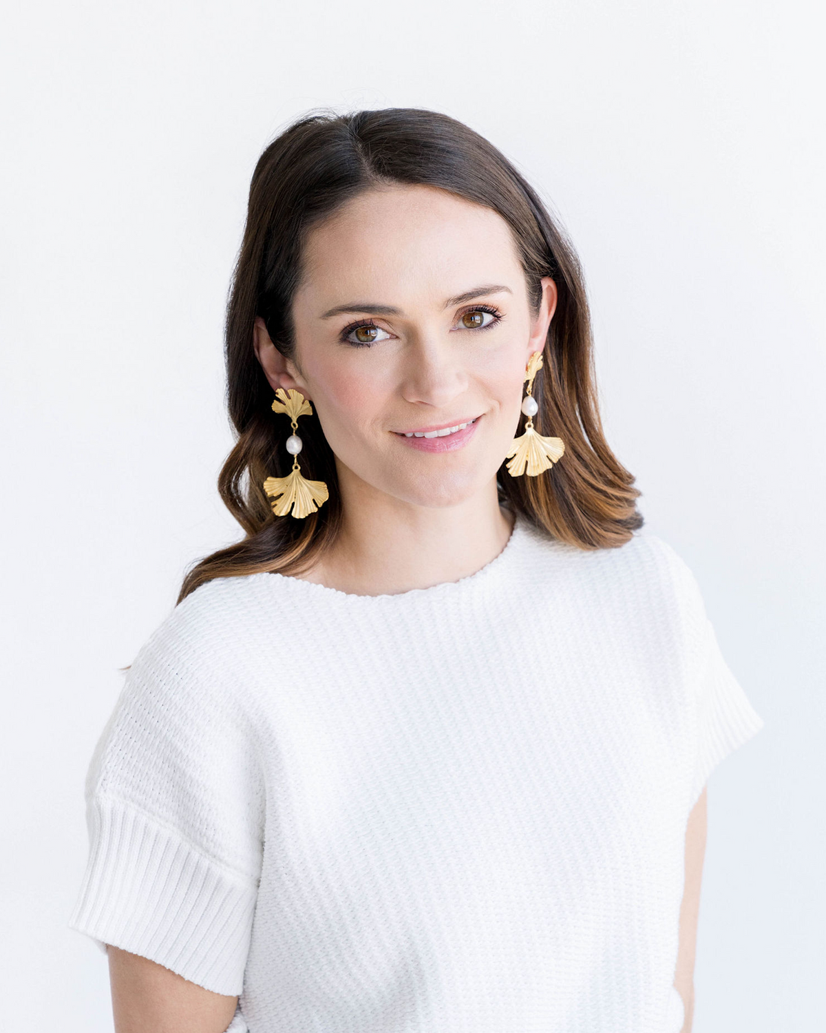 Triple-plated gold ginkgo leaf earrings featuring a freshwater pearl detail.