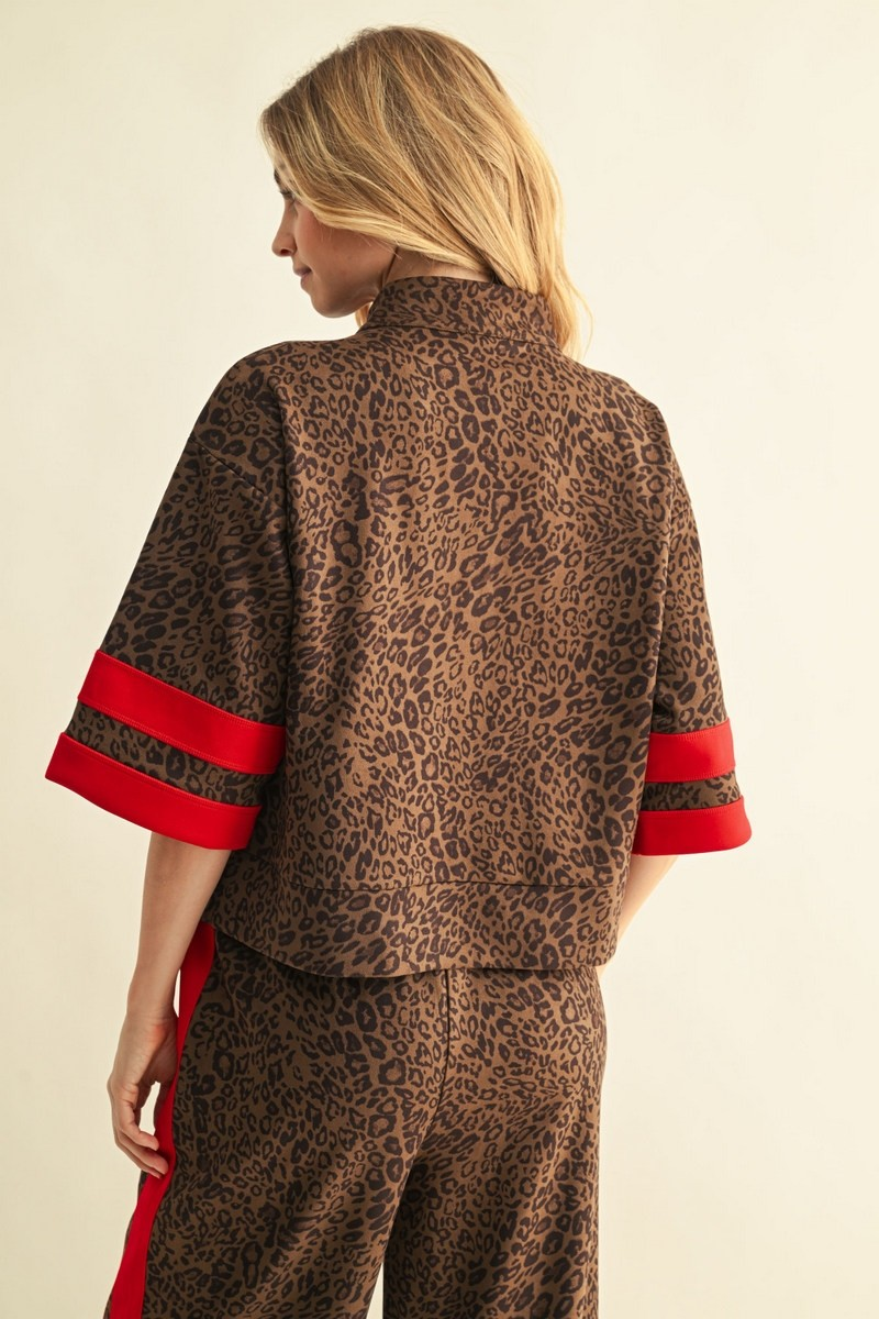 Back view of a woman wearing a leopard print faux suede top with red striped sleeve details.