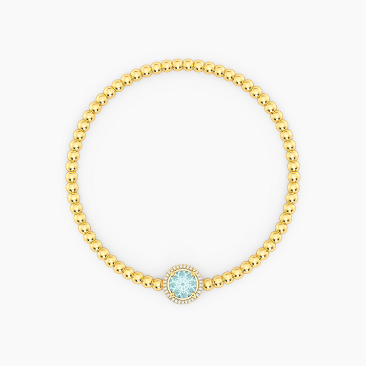 Gold plated beaded bracelet with a round-cut light blue gemstone and diamond halo charm.