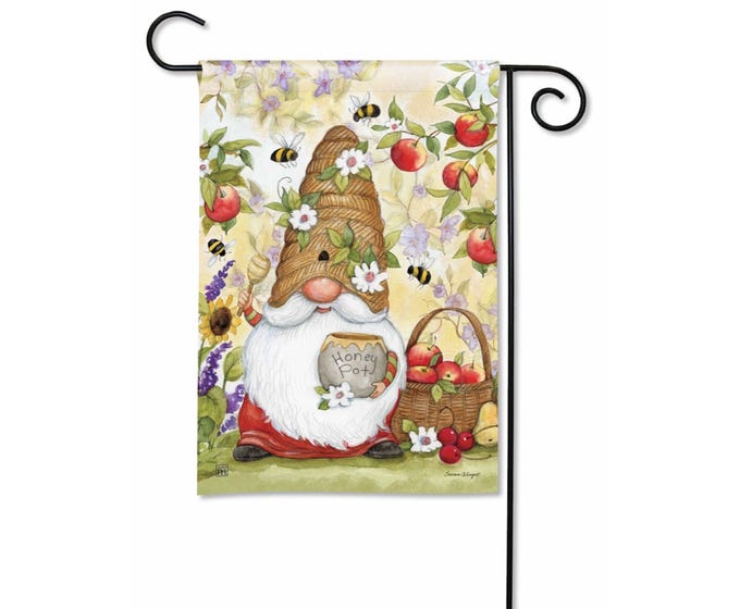 A garden flag featuring a gnome wearing a beehive hat and holding a honey pot amidst bees and fruit.