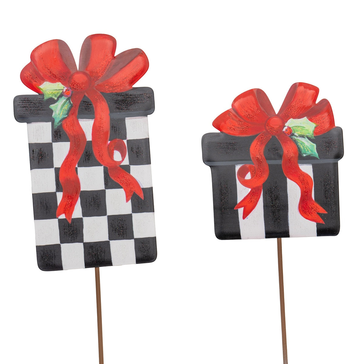 Two decorative gift box stakes with red bows and holly. One has a black and white checkerboard pattern, the other has black and white stripes.