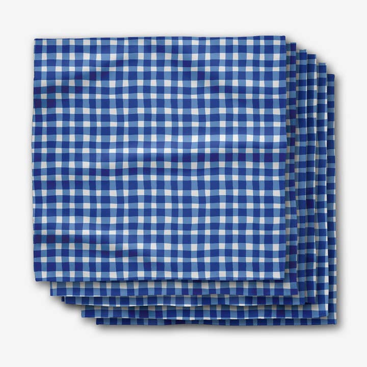 Set of six blue and white gingham check dinner napkins stacked on a white background.