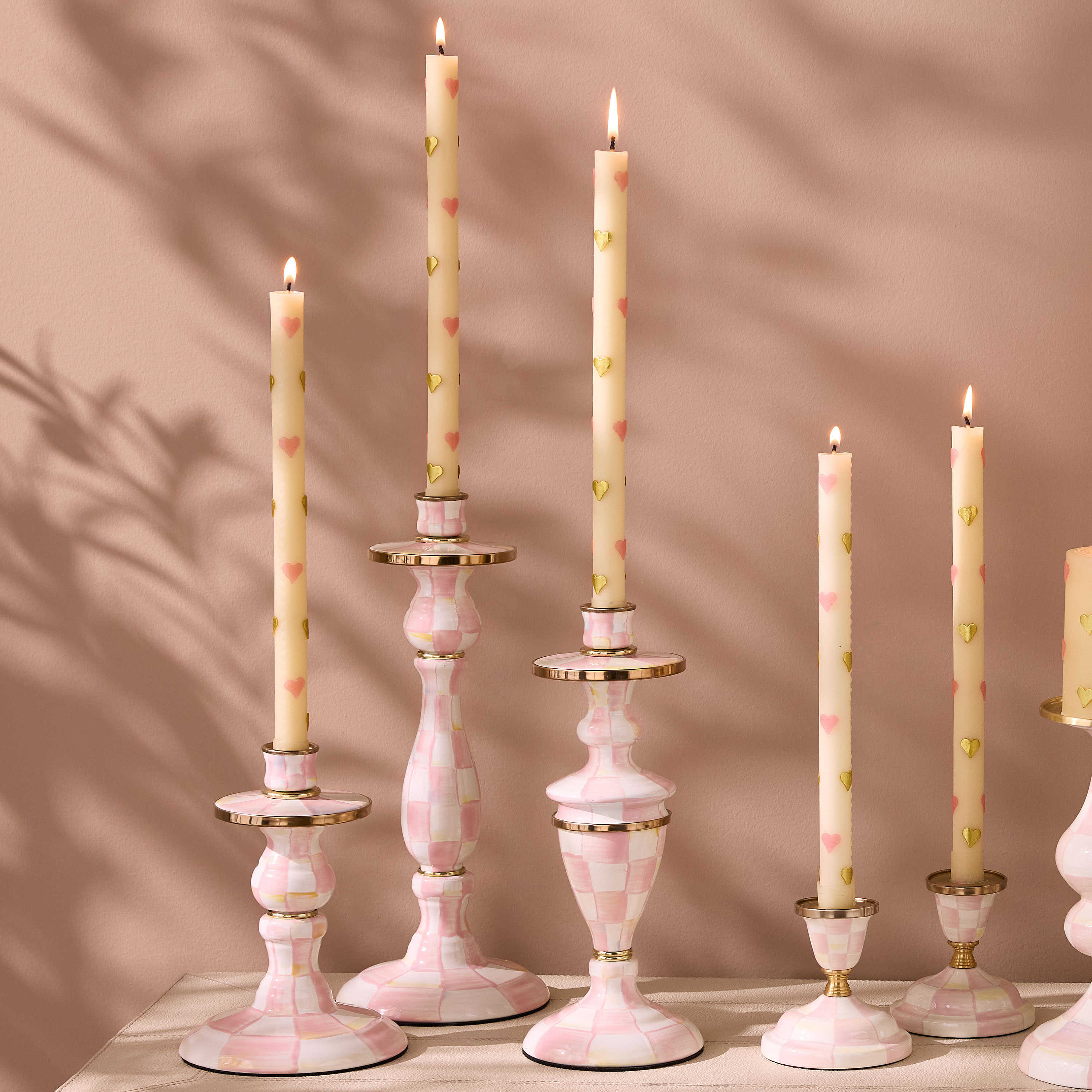 Hand-painted pink and white checkered candlesticks with brass accents and heart-patterned candles.