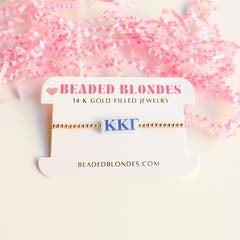 Kappa Kappa Gamma symbol bracelet on a white display card with pink shredded paper background.
