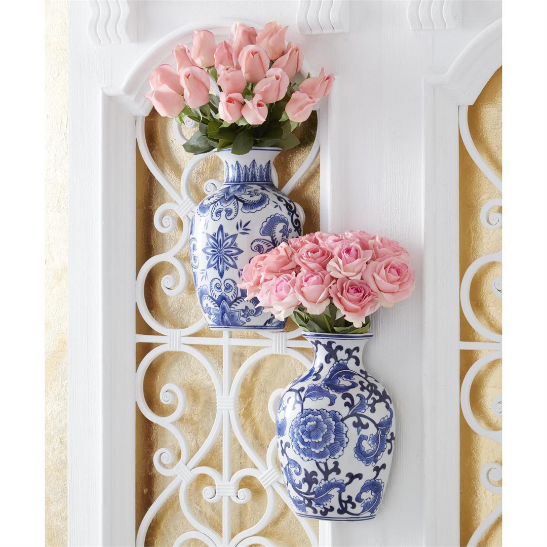Two blue and white chinoiserie porcelain wall vases with pink roses on a white decorative screen.