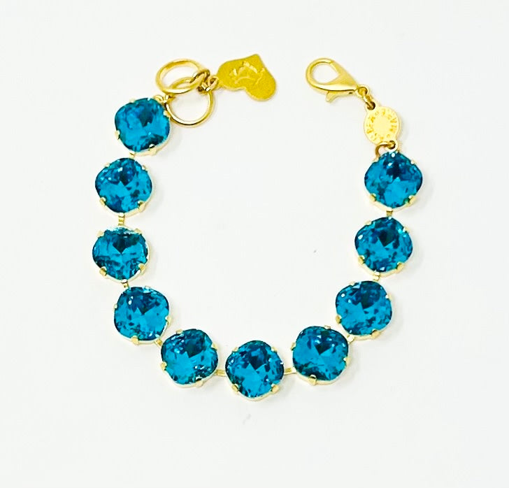 Gold Premier Bracelet with round Santorini blue crystals and a heart charm.