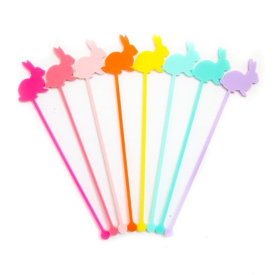 Eight colorful acrylic rainbow bunny drink stirrers standing upright.